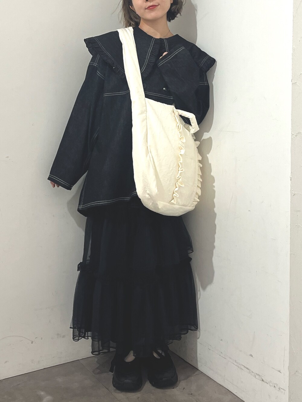 ホワイト系のトートバッグ、ブルー系のデニムジャケット、ブラック系のスカートを着用したレディースの秋コーディネートの2枚目の写真