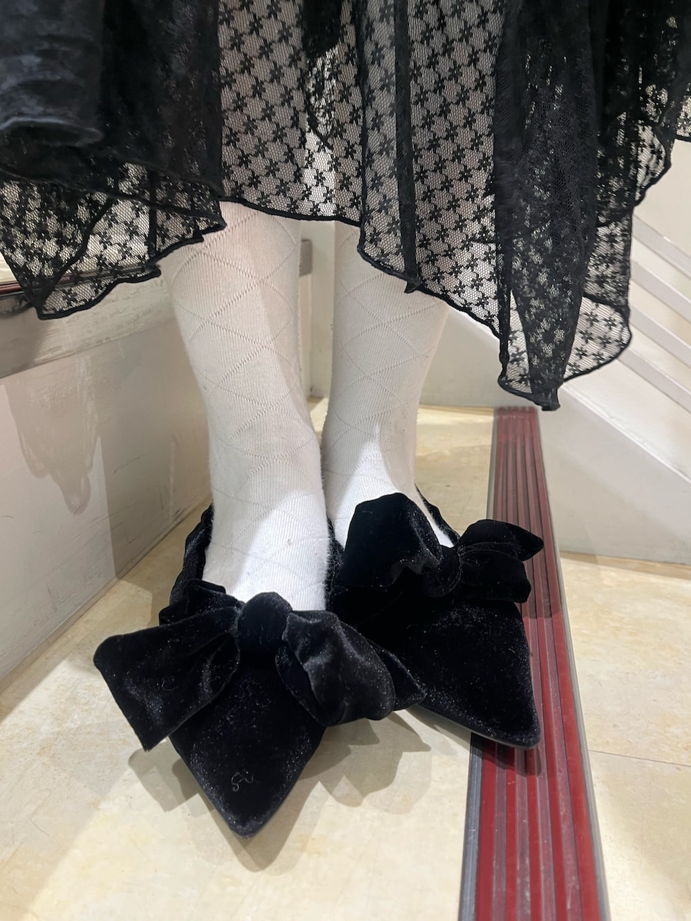 ブラック系のワンピース、ホワイト系のニット/セーター、ブラック系のパンプスを着用したレディースの冬コーディネートの10枚目の写真