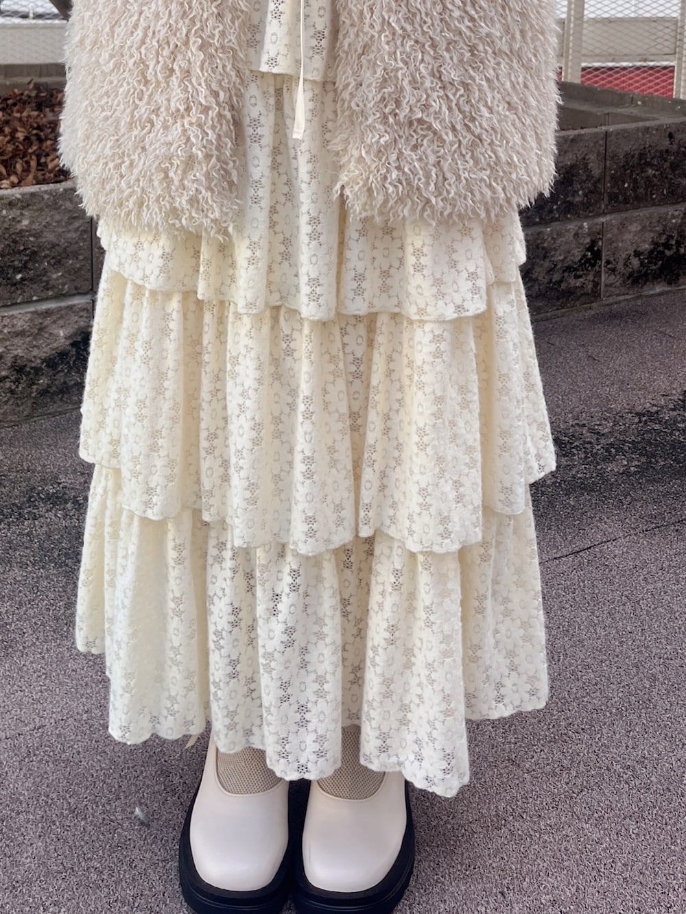 ベージュ系のダウンベスト、ホワイト系のシャツ/ブラウス、ホワイト系のスカートを着用したレディースの秋コーディネートの6枚目の写真