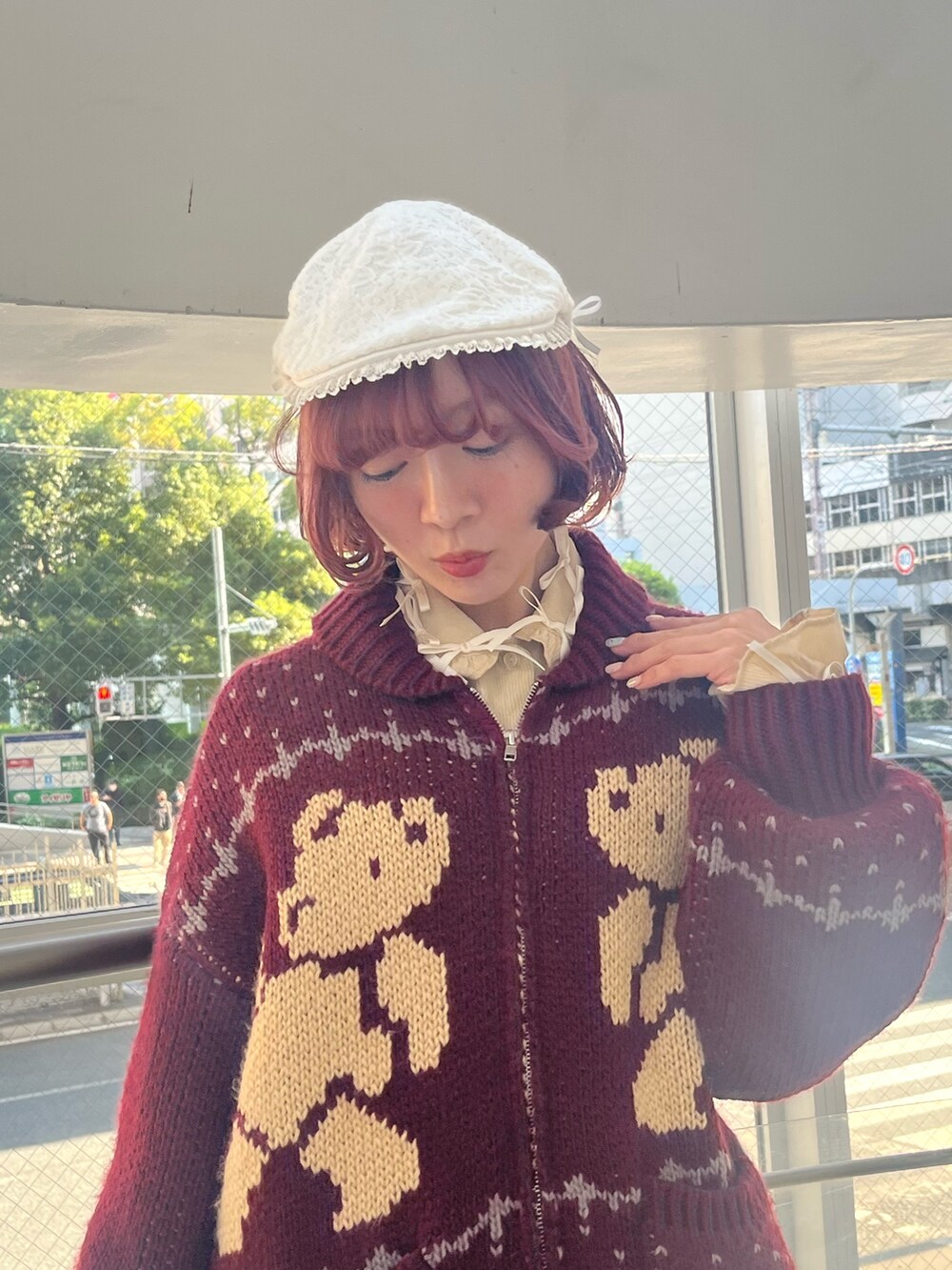 レッド系のカーディガン/ボレロ、グレー系のスカート、ブラック系のブーツを着用したレディースの秋コーディネートの5枚目の写真