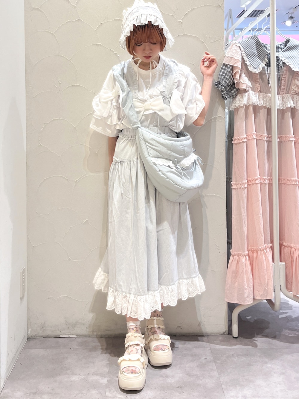 ブルー系のショルダーバッグ、ホワイト系のTシャツ/カットソー、ブルー系のジャンパースカートを着用したレディースの夏コーディネートの2枚目の写真