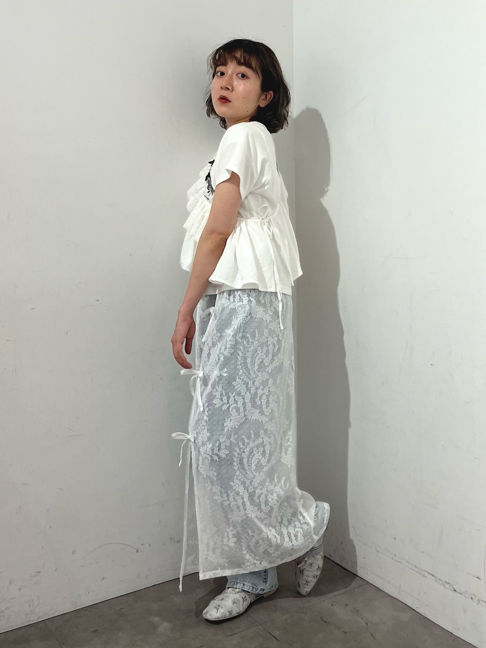 ホワイト系のスカート、ホワイト系のTシャツ/カットソー、ブルー系のデニムパンツを着用したレディースの春コーディネートの3枚目の写真