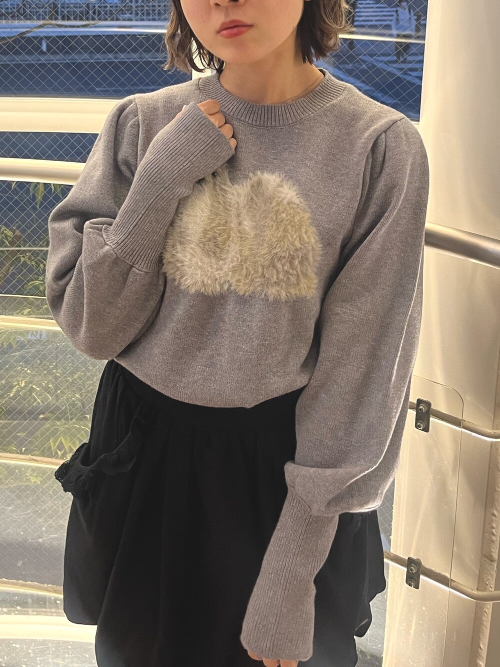 グレー系のニット/セーター、ブラック系のMA-1、ブラック系のスカートを着用したレディースの秋コーディネートの7枚目の写真