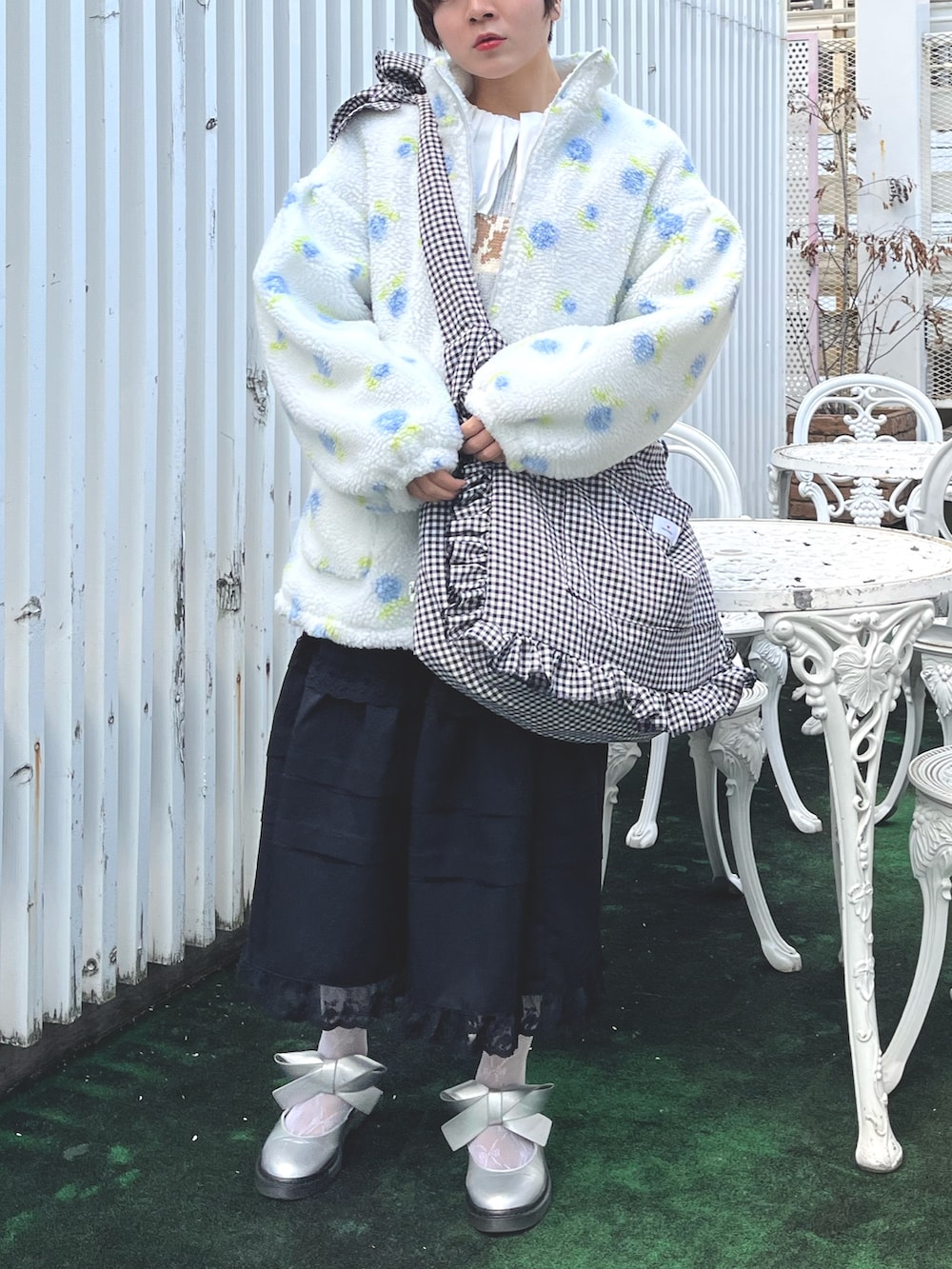 ブラック系のショルダーバッグ、ブルー系のニット/セーター、ホワイト系のシャツ/ブラウスを着用したレディースの冬コーディネートの2枚目の写真