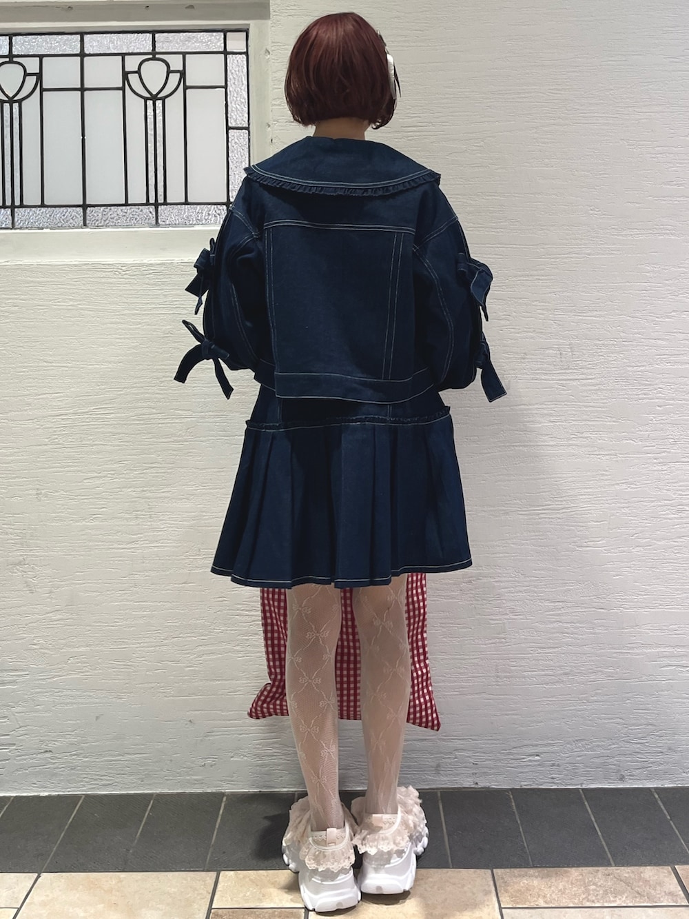 ブルー系のスカート、ブルー系のデニムジャケット、レッド系のトートバッグを着用したレディースの秋コーディネートの4枚目の写真