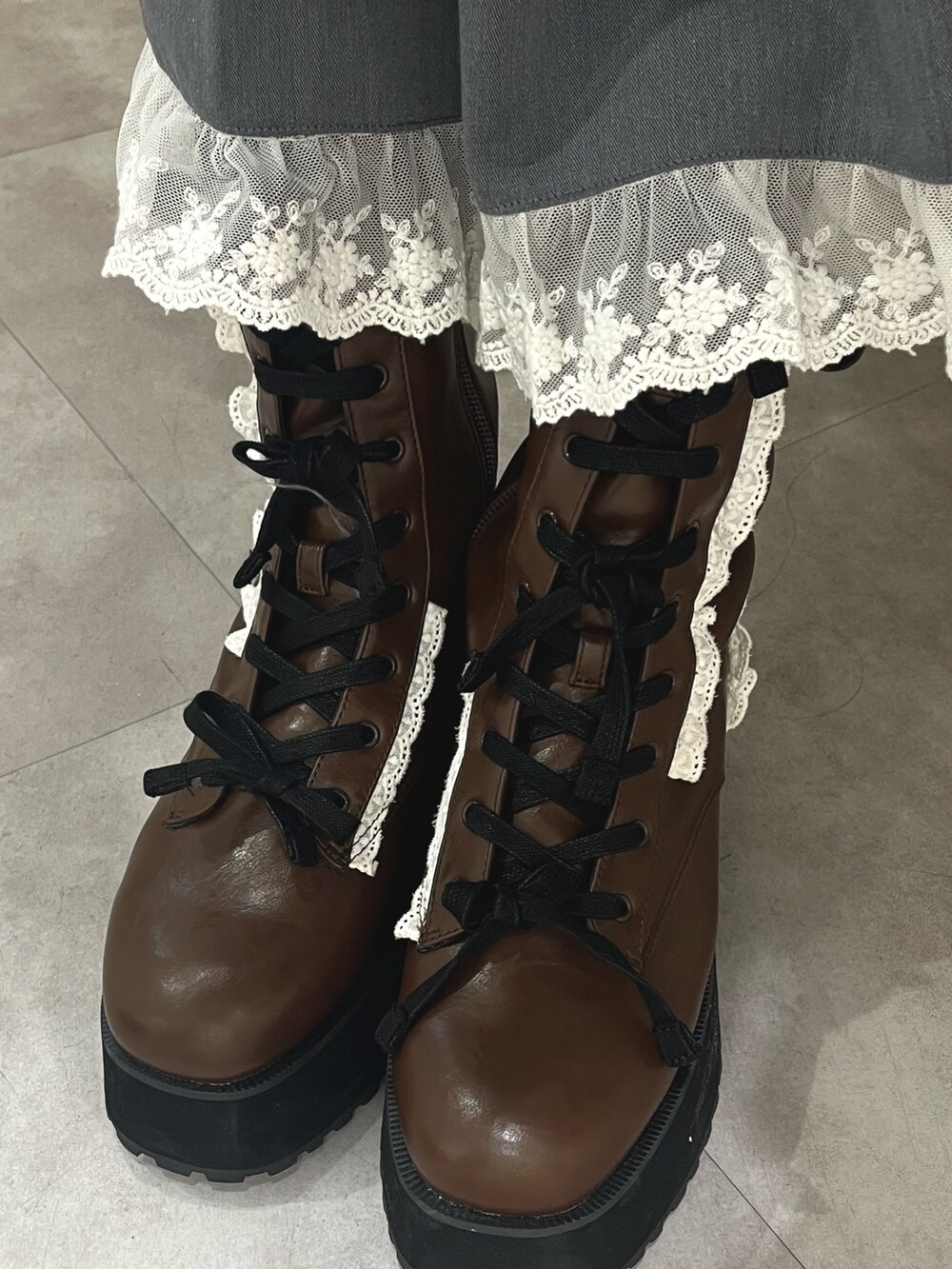 レッド系のカーディガン/ボレロ、グレー系のスカート、ブラック系のブーツを着用したレディースの秋コーディネートの8枚目の写真