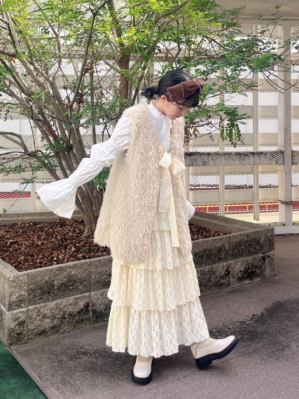 ベージュ系のダウンベスト、ホワイト系のシャツ/ブラウス、ホワイト系のスカートを着用したレディースの秋コーディネートの2枚目の写真