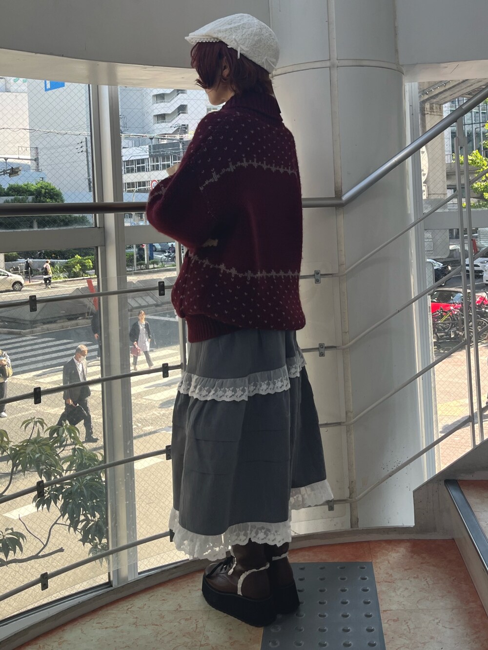 レッド系のカーディガン/ボレロ、グレー系のスカート、ブラック系のブーツを着用したレディースの秋コーディネートの4枚目の写真