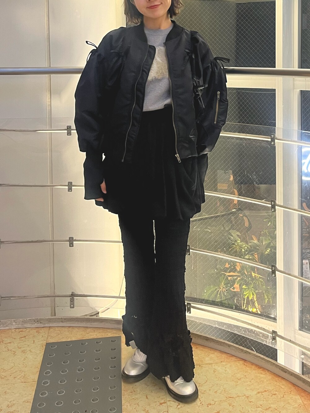 グレー系のニット/セーター、ブラック系のMA-1、ブラック系のスカートを着用したレディースの秋コーディネートの2枚目の写真