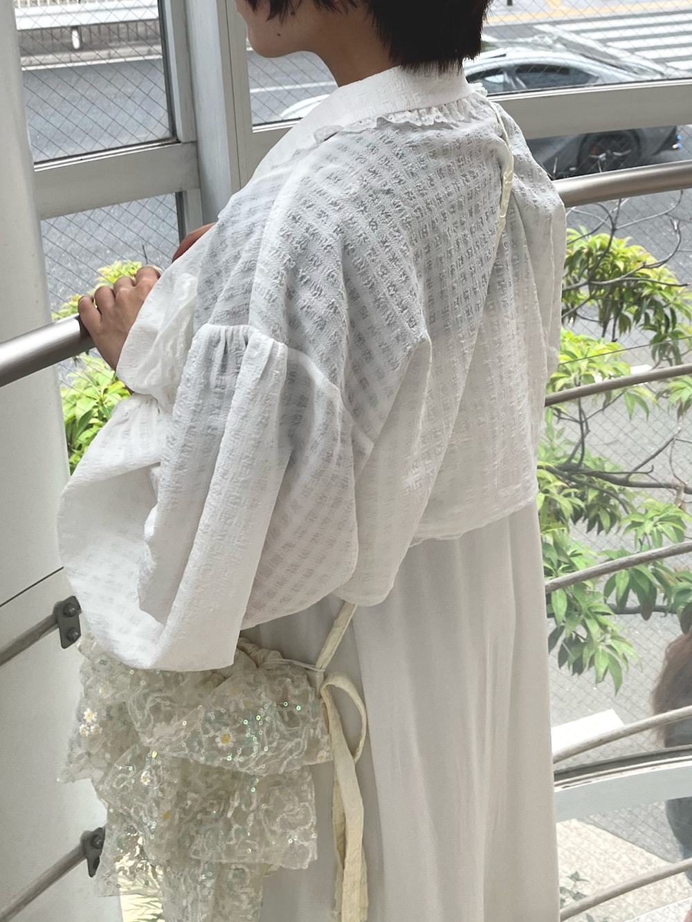 ブラック系のスニーカー、ブラック系のニット/セーター、ホワイト系のワンピースを着用したレディースの春コーディネートの6枚目の写真