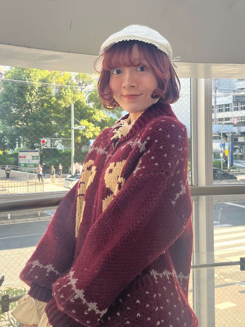 レッド系のカーディガン/ボレロ、グレー系のスカート、ブラック系のブーツを着用したレディースの秋コーディネートの6枚目の写真