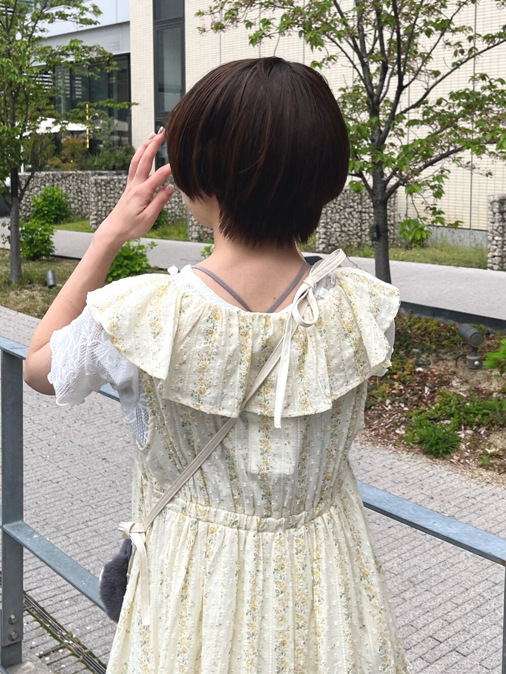 イエロー系のワンピース、ホワイト系のTシャツ/カットソー、グレー系のショルダーバッグを着用したレディースの春コーディネートの6枚目の写真