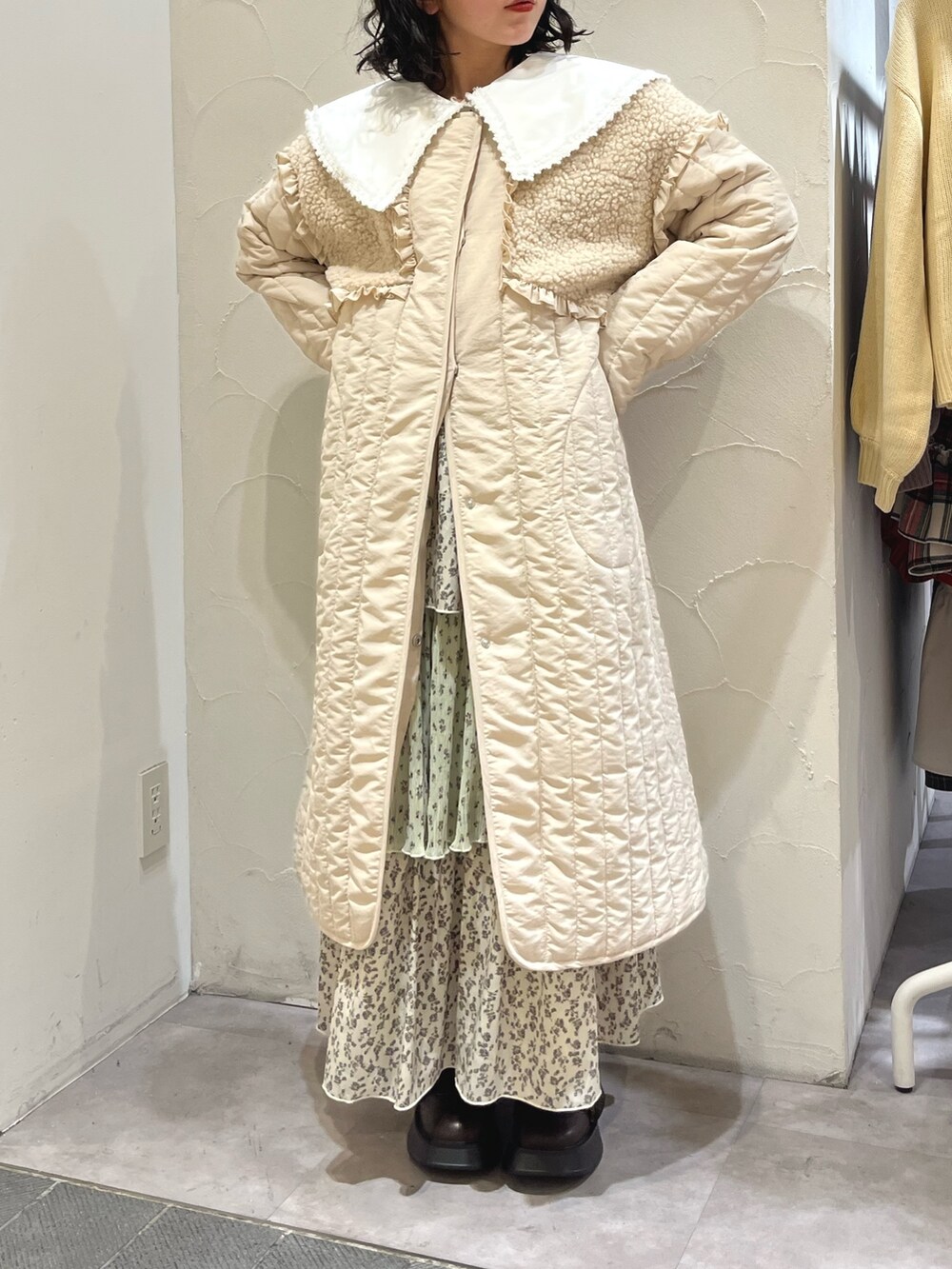 ホワイト系のステンカラーコート、グリーン系のスカート、ブラウン系のブーツを着用したレディースの秋コーディネートの2枚目の写真