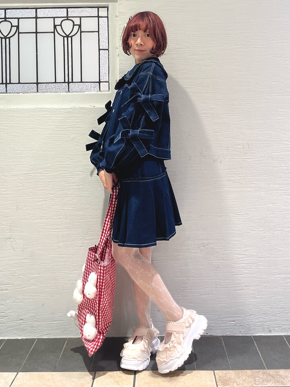 ブルー系のスカート、ブルー系のデニムジャケット、レッド系のトートバッグを着用したレディースの秋コーディネートの3枚目の写真