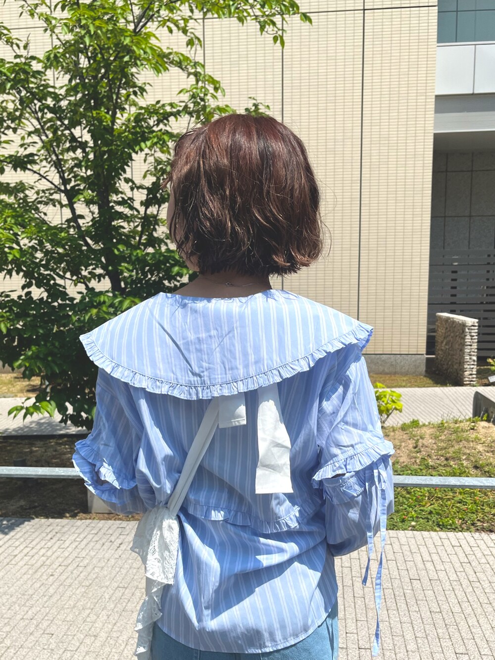 ブルー系のシャツ/ブラウス、ホワイト系のトートバッグ、ブルー系のデニムパンツを着用したレディースの夏コーディネートの5枚目の写真