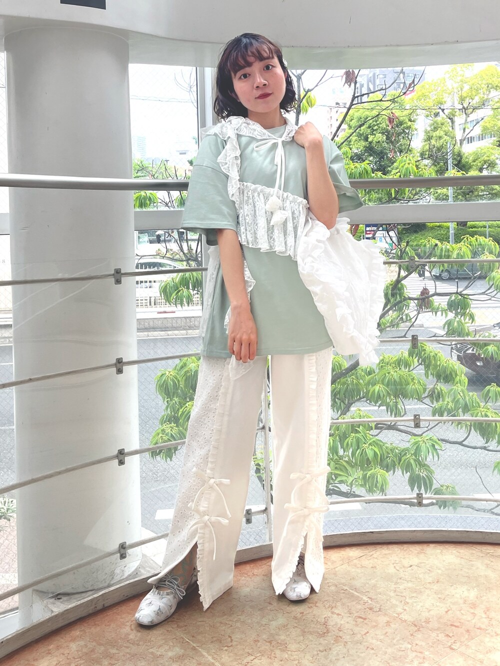 グリーン系のTシャツ/カットソー、ホワイト系のトートバッグ、ホワイト系のデニムパンツを着用したレディースの春コーディネートの2枚目の写真