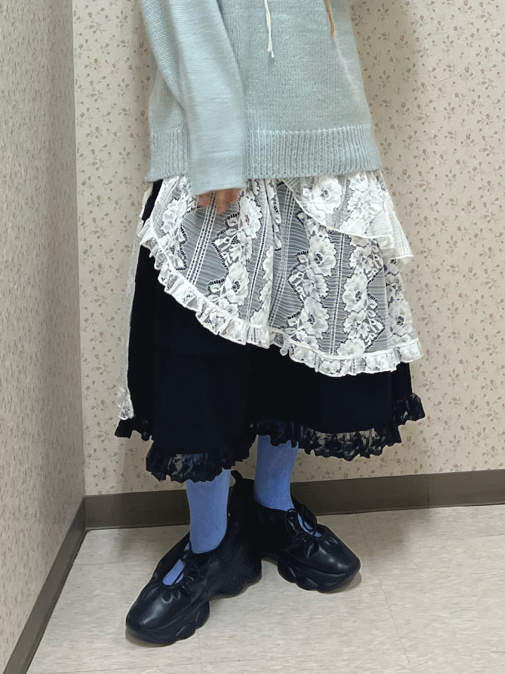 ブルー系のニット/セーター、ホワイト系のスカート、ブラック系のスカートを着用したレディースの秋コーディネートの7枚目の写真