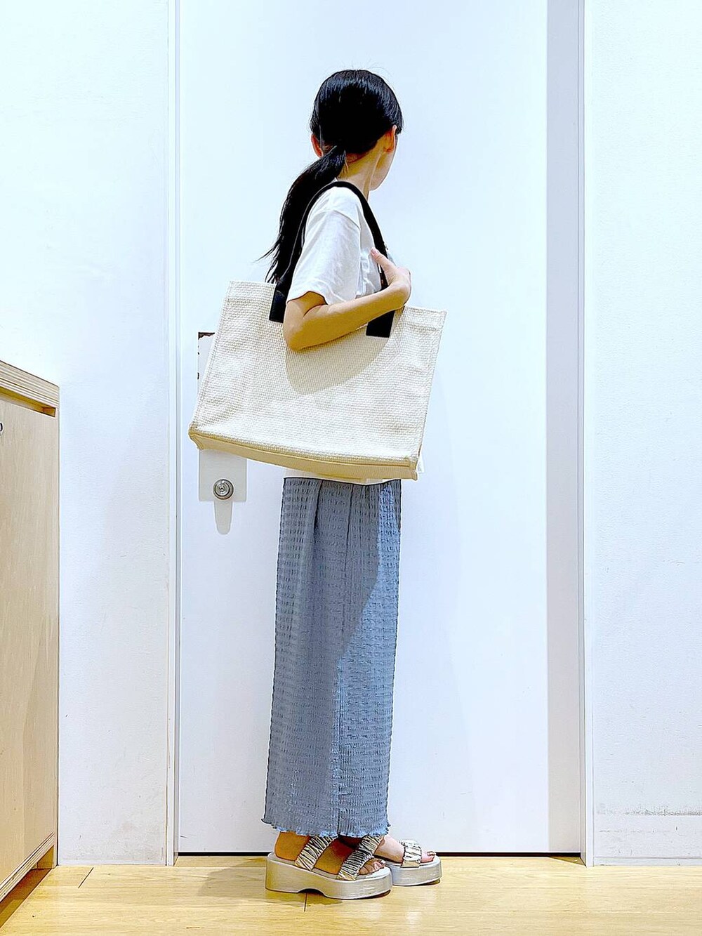 シルバー系のサンダル、ブルー系のスカート、ホワイト系のトートバッグを着用したレディースの夏コーディネートの4枚目の写真