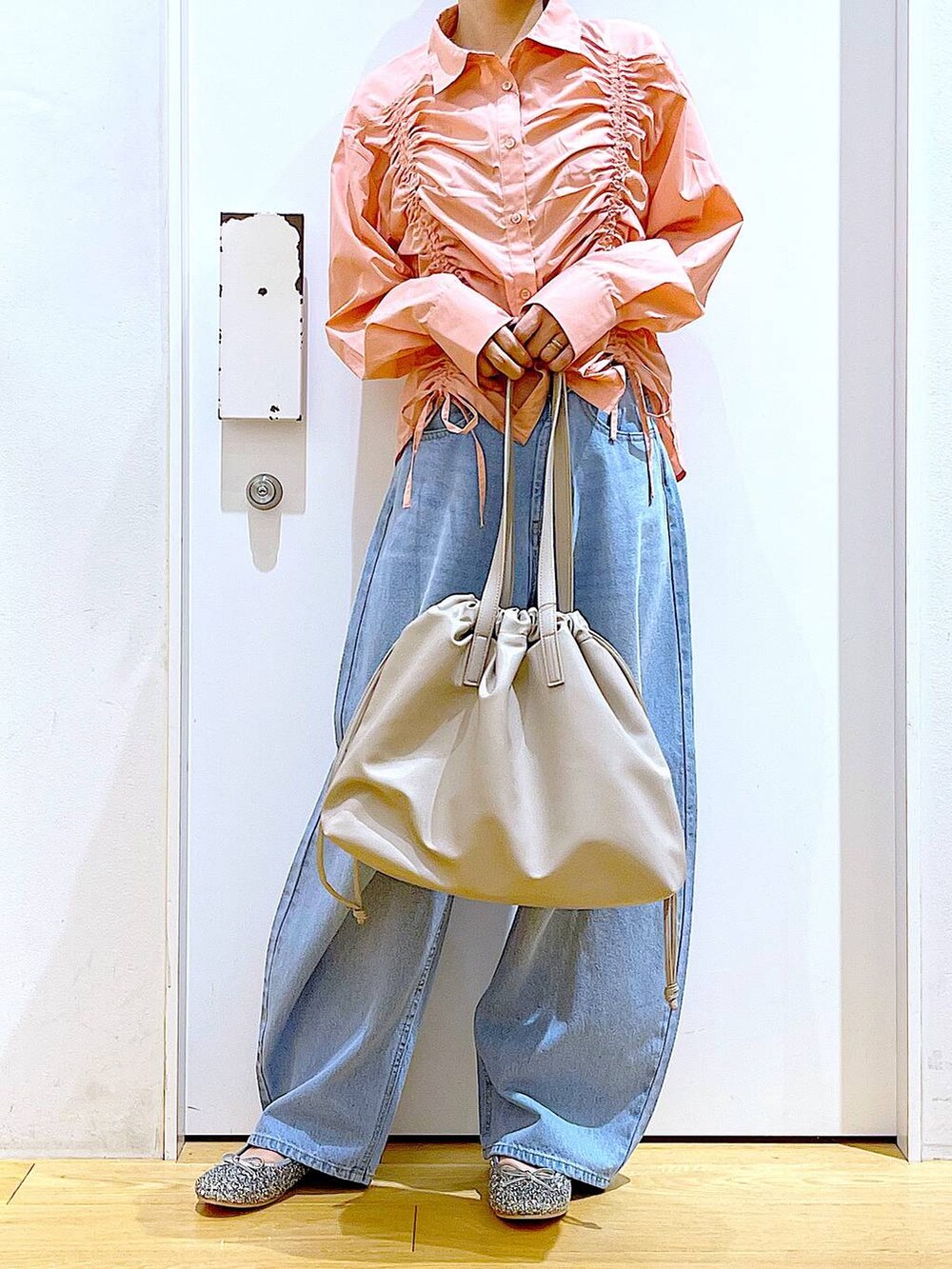 ベージュ系のトートバッグ、ブルー系のデニムパンツ、シルバー系のパンプスを着用したレディースの秋コーディネートの6枚目の写真