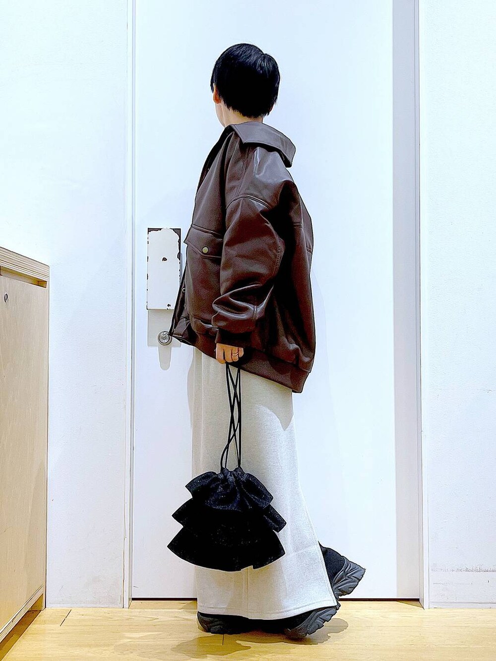 ブラウン系のブルゾン、ブラック系のブーツ、ブラック系のショルダーバッグを着用したレディースの冬コーディネートの3枚目の写真