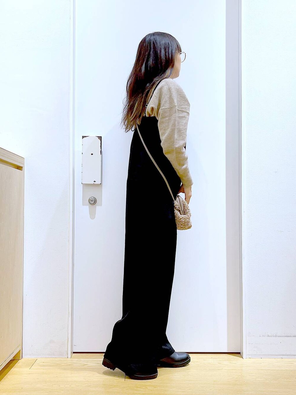 ベージュ系のニット/セーター、ブラック系のブーツ、ブラウン系のクラッチバッグを着用したレディースの冬コーディネートの4枚目の写真