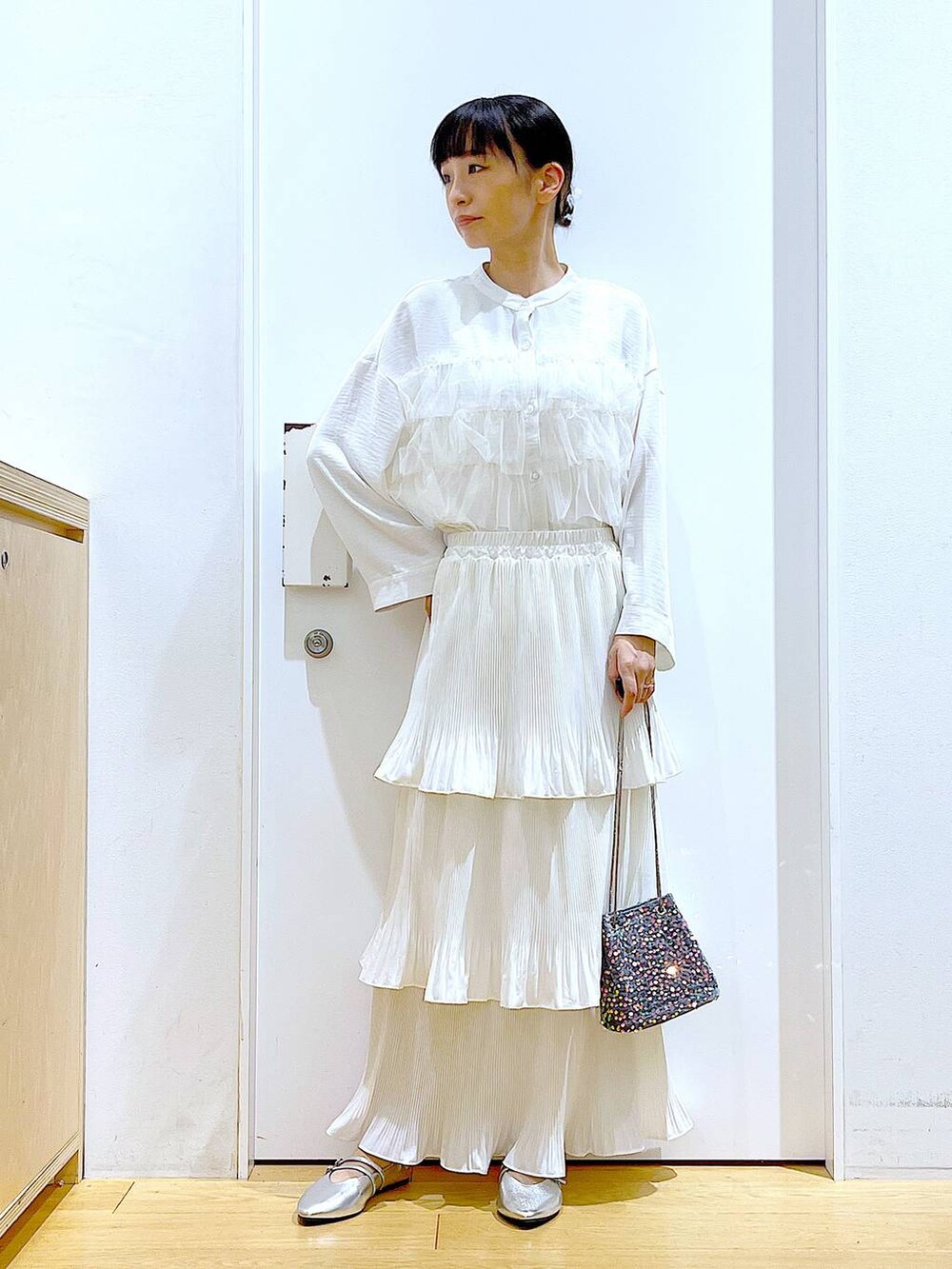 ベージュ系のスカート、シルバー系のパンプス、ホワイト系のシャツ/ブラウスを着用したレディースの秋コーディネートの2枚目の写真