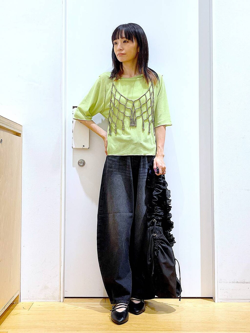 グリーン系のTシャツ/カットソー、ブラック系のデニムパンツ、ブラック系のパンプスを着用したレディースの秋コーディネートの2枚目の写真