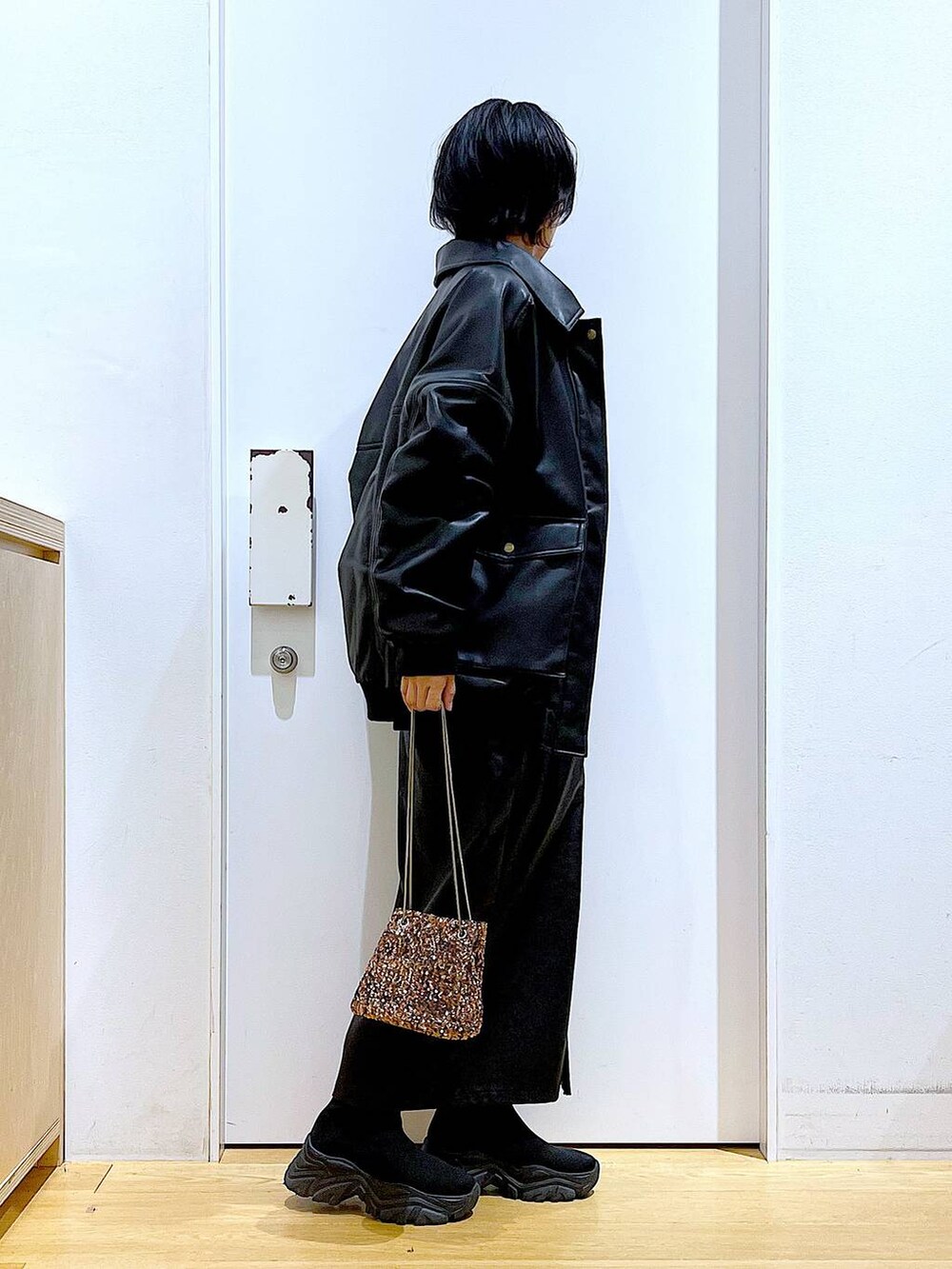 オレンジ系のニット/セーター、ブラウン系のスカート、ブラック系のブーツを着用したレディースの冬コーディネートの4枚目の写真