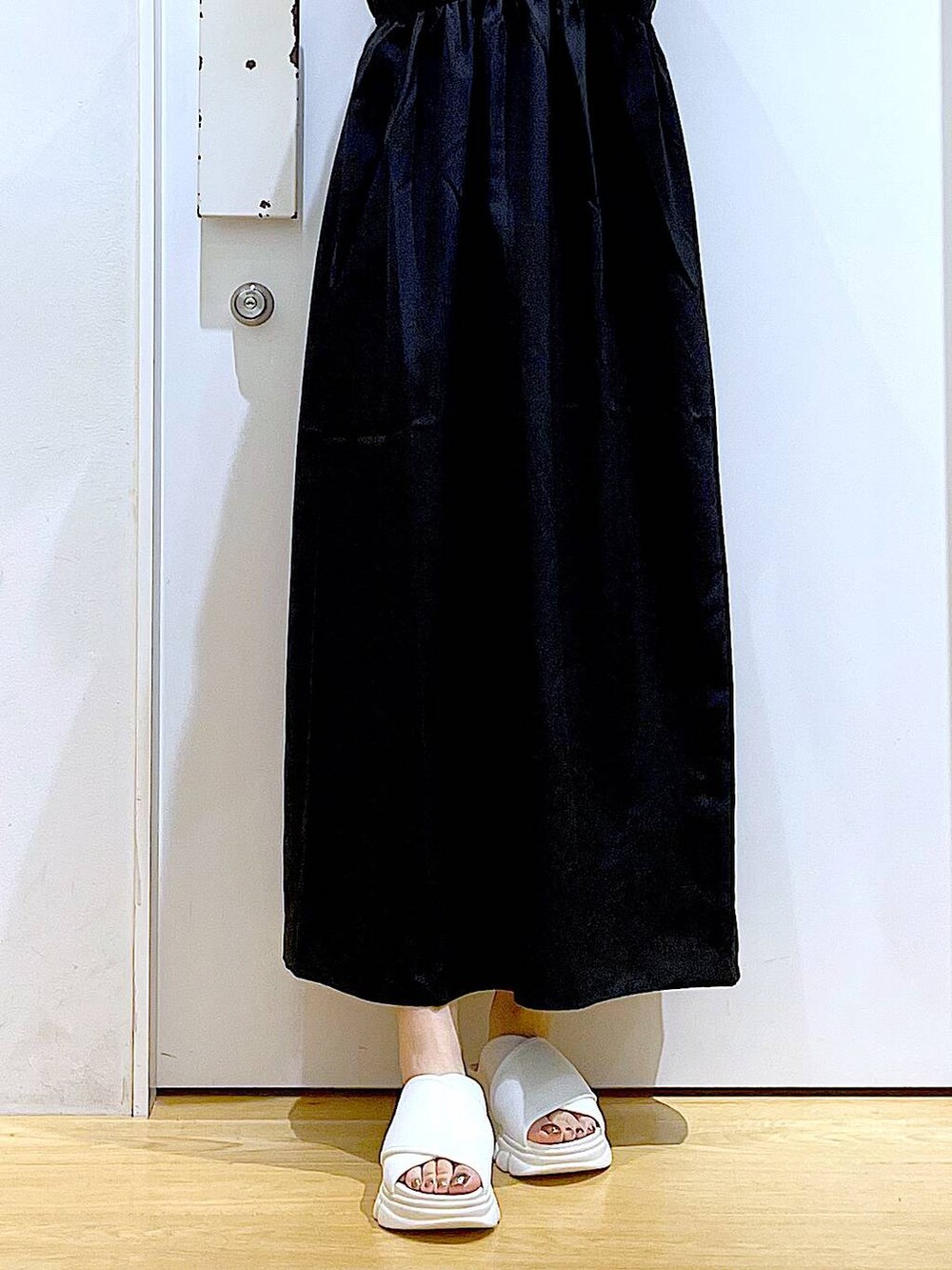 ホワイト系のサンダル、ベージュ系のTシャツ/カットソー、ブラック系のワンピースを着用したレディースの夏コーディネートの7枚目の写真