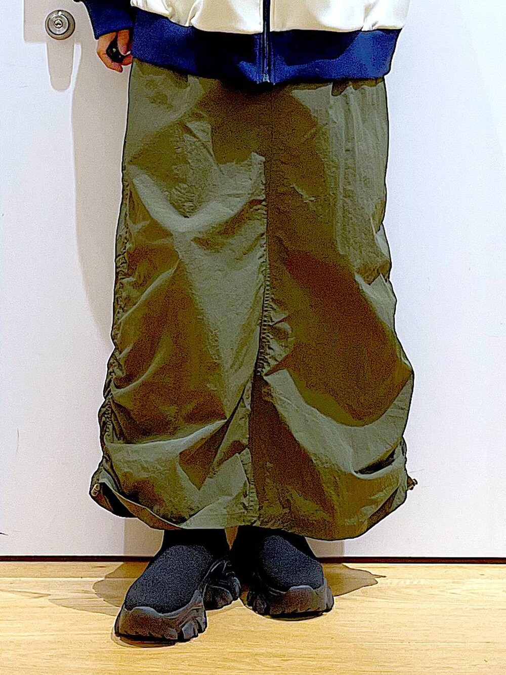 ホワイト系のトートバッグ、ブラック系のブーツ、グリーン系のスカートを着用したレディースの冬コーディネートの8枚目の写真