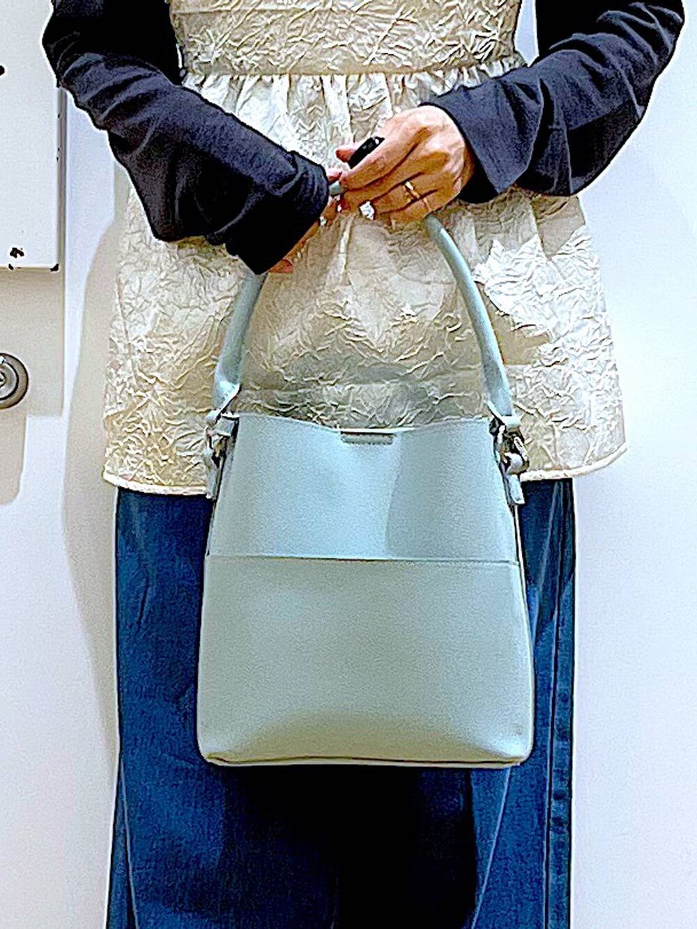ブルー系のデニムパンツ、ホワイト系のキャミソール、グリーン系のショルダーバッグを着用したレディースの春コーディネートの9枚目の写真