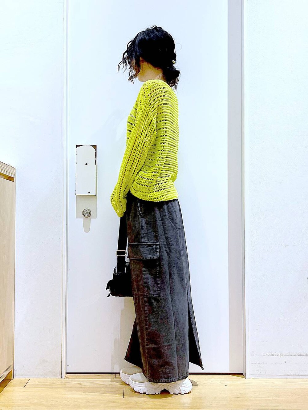 グレー系のデニムスカート、ベージュ系のスニーカー、ブラック系のショルダーバッグを着用したレディースの春コーディネートの3枚目の写真