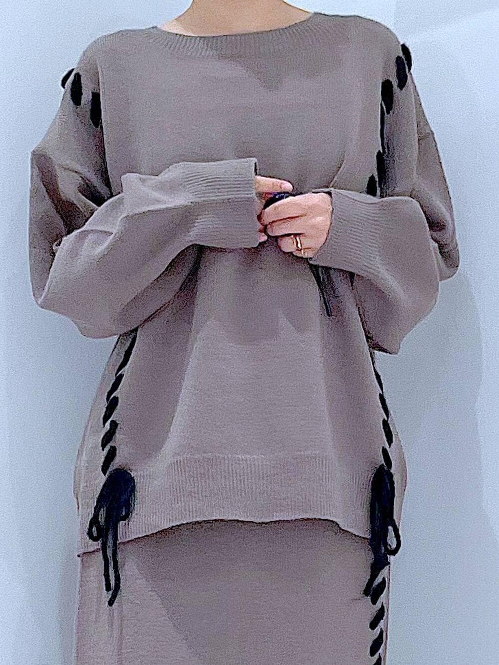 ブラウン系のニット/セーター、ブラウン系のスカート、ブラック系のブーツを着用したレディースの秋コーディネートの7枚目の写真