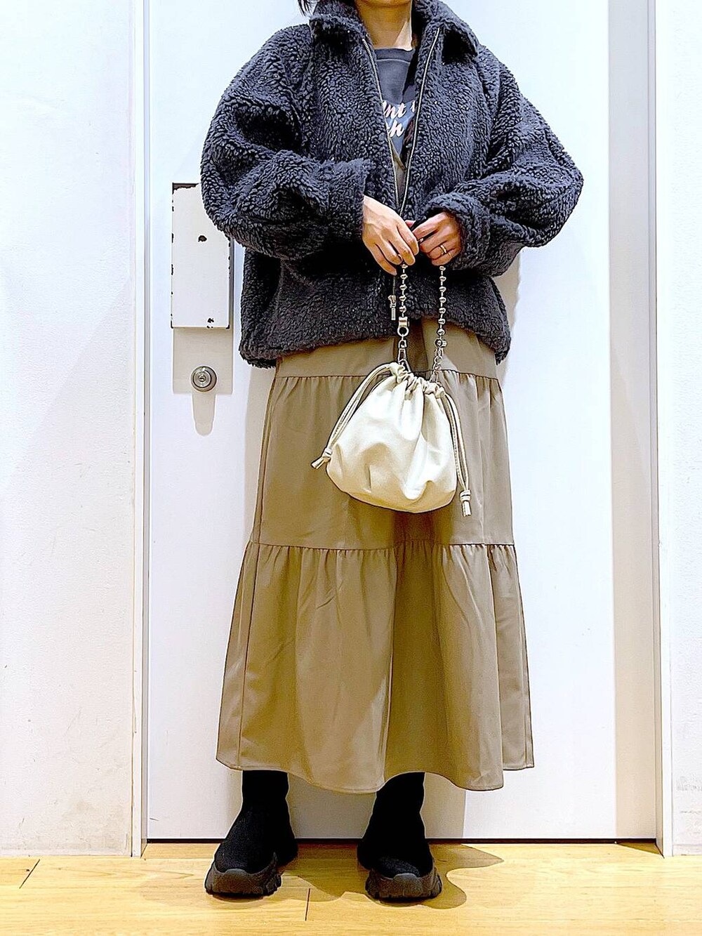 ベージュ系のショルダーバッグ、ブラック系のブーツ、ブラウン系のワンピースを着用したレディースの冬コーディネートの6枚目の写真