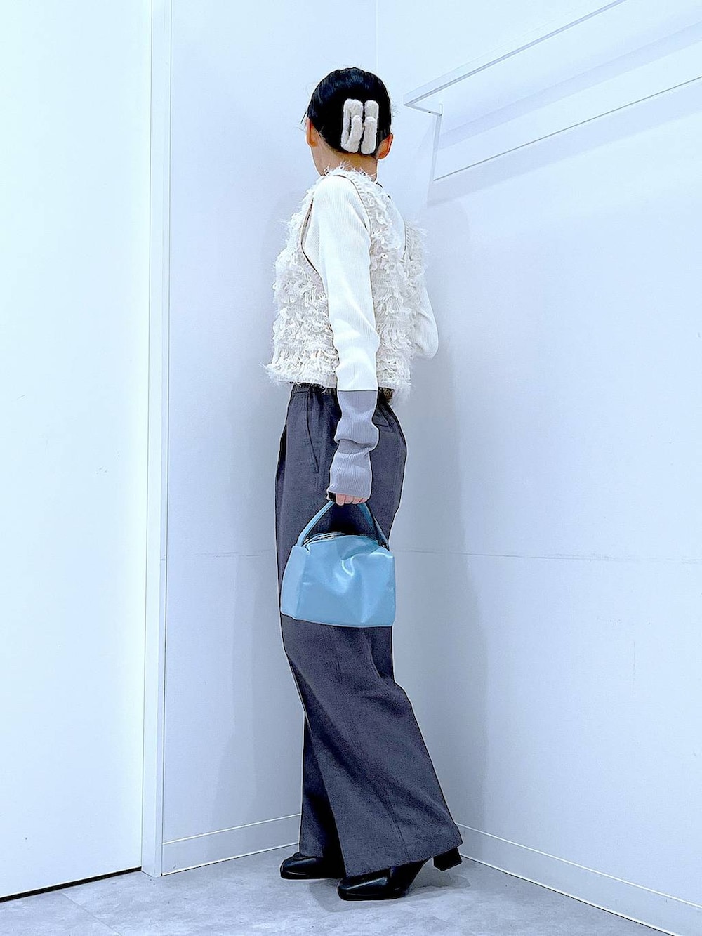 ブラック系のブーツ、グレー系のスラックス、ホワイト系のベストを着用したレディースの冬コーディネートの3枚目の写真