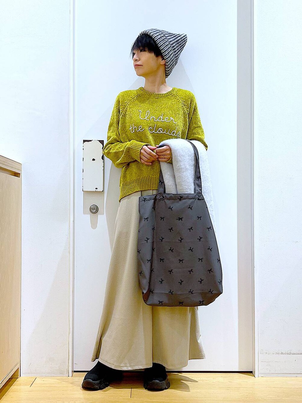 ブラック系のブーツ、その他のトートバッグ、グレー系のスカートを着用したレディースの冬コーディネートの2枚目の写真