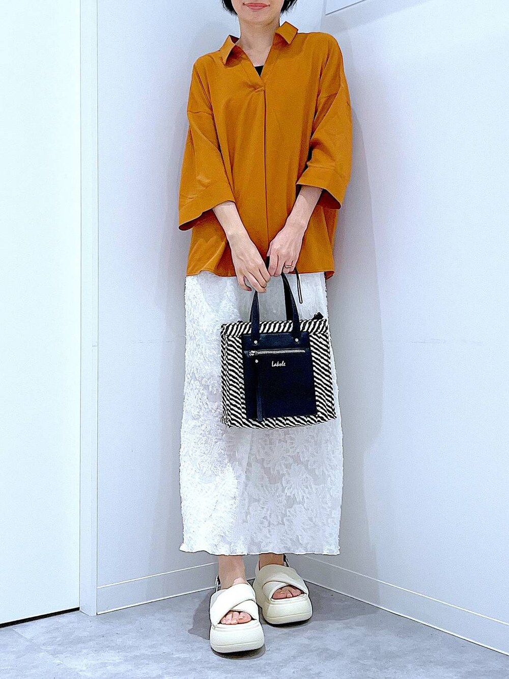 ブラック系のショルダーバッグ、ホワイト系のサンダル、ホワイト系のスカートを着用したレディースの夏コーディネートの6枚目の写真