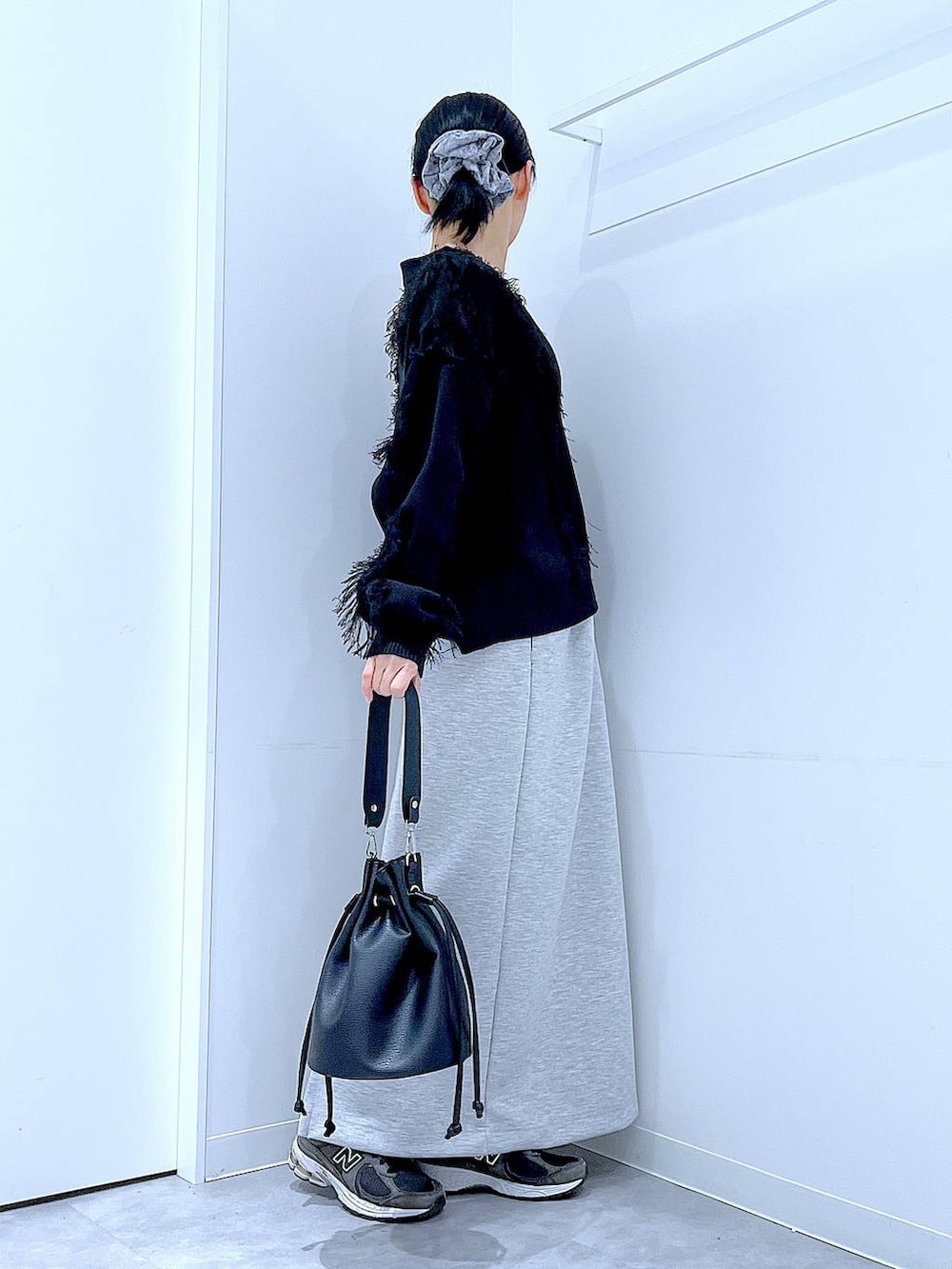 グレー系のスカート、ブラック系のショルダーバッグ、ブラック系のカーディガン/ボレロを着用したレディースの春コーディネートの4枚目の写真