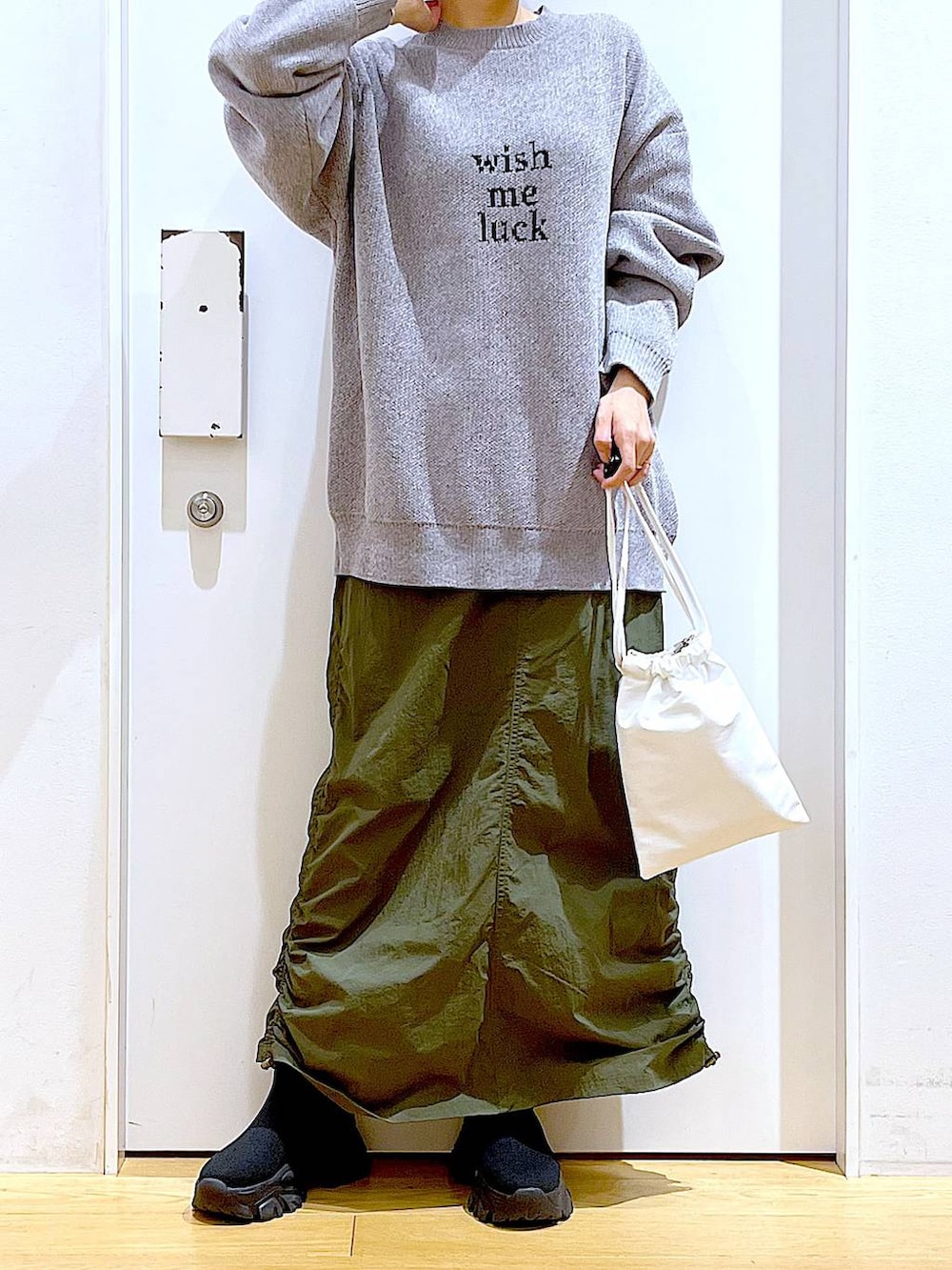 ブラック系のブーツ、グレー系のニット/セーター、グリーン系のスカートを着用したレディースの冬コーディネートの6枚目の写真