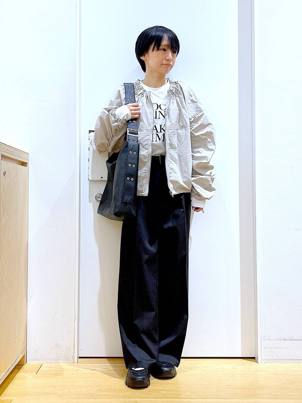 ブラック系のスラックス、ブラック系のスニーカー、ブラック系のショルダーバッグを着用したレディースの春コーディネートの2枚目の写真