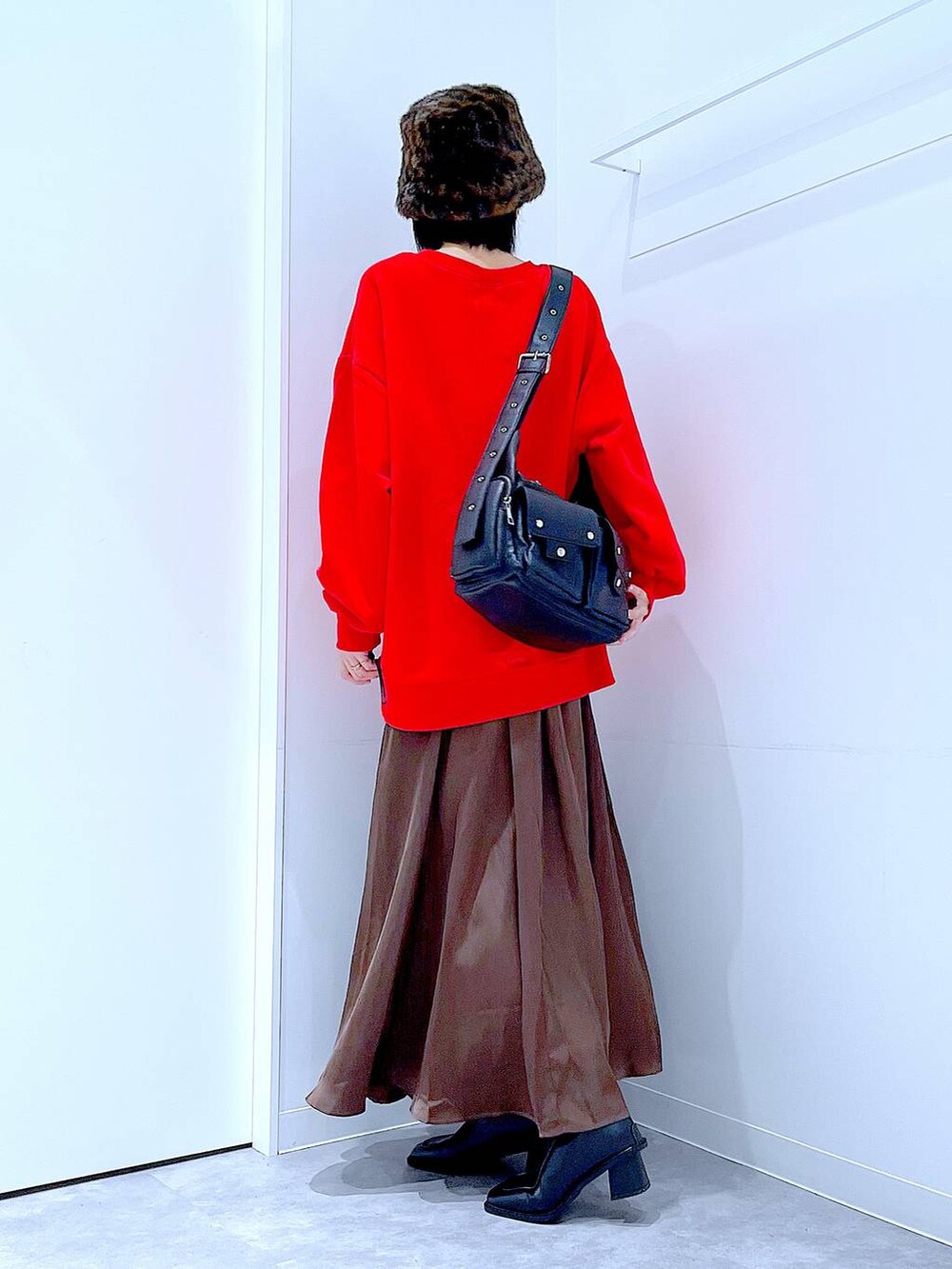 ブラック系のショルダーバッグ、ブラック系のブーツ、レッド系のスウェットを着用したレディースの秋コーディネートの3枚目の写真