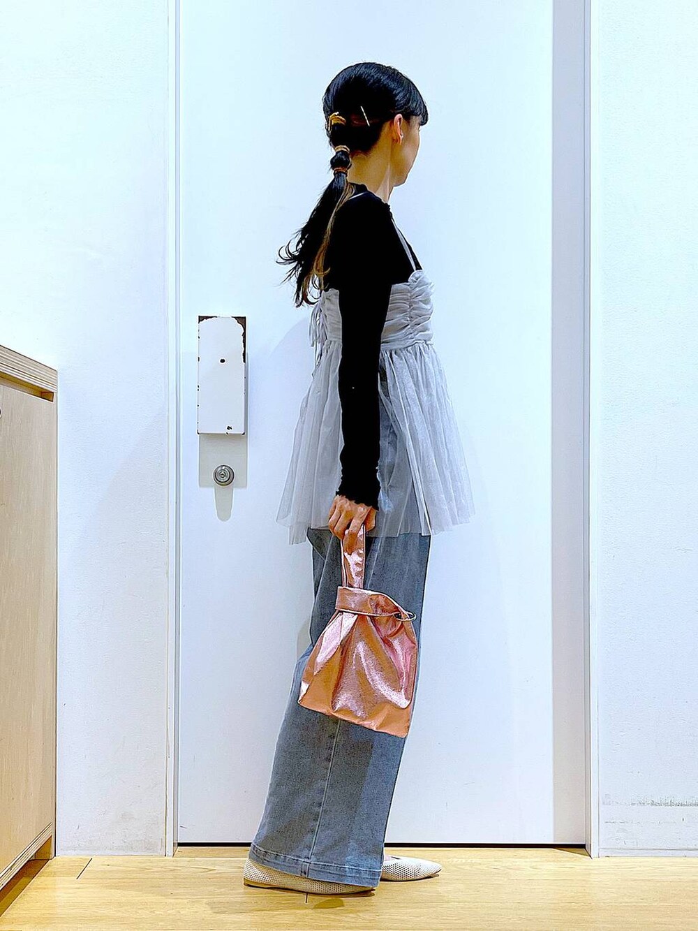 ブルー系のデニムパンツ、ピンク系のショルダーバッグ、ホワイト系のパンプスを着用したレディースの春コーディネートの4枚目の写真