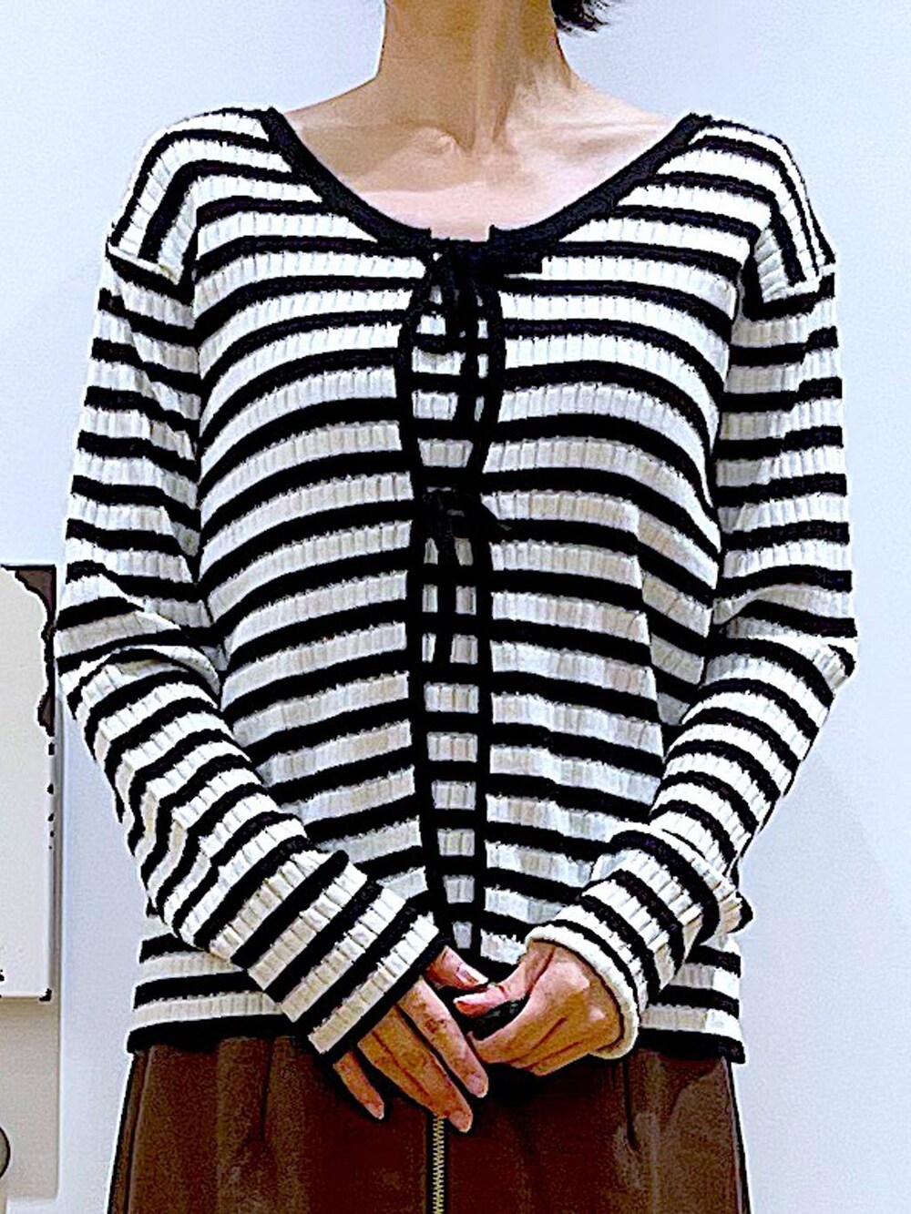 ブラウン系のスカート、ホワイト系のショルダーバッグ、ブラック系のブーツを着用したレディースの秋コーディネートの7枚目の写真