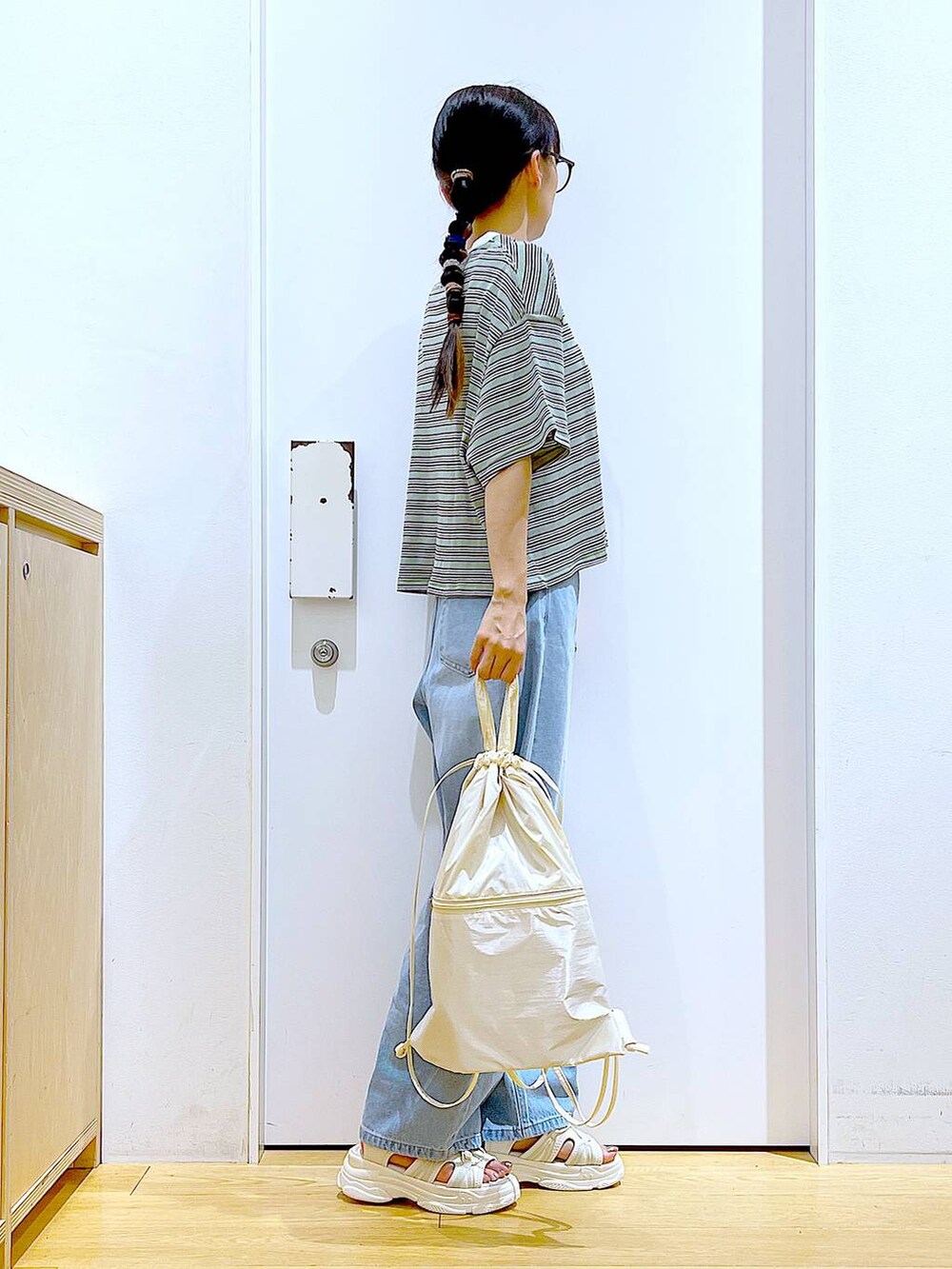 ホワイト系のバックパック/リュック、ホワイト系のサンダル、ブルー系のデニムパンツを着用したレディースの夏コーディネートの4枚目の写真