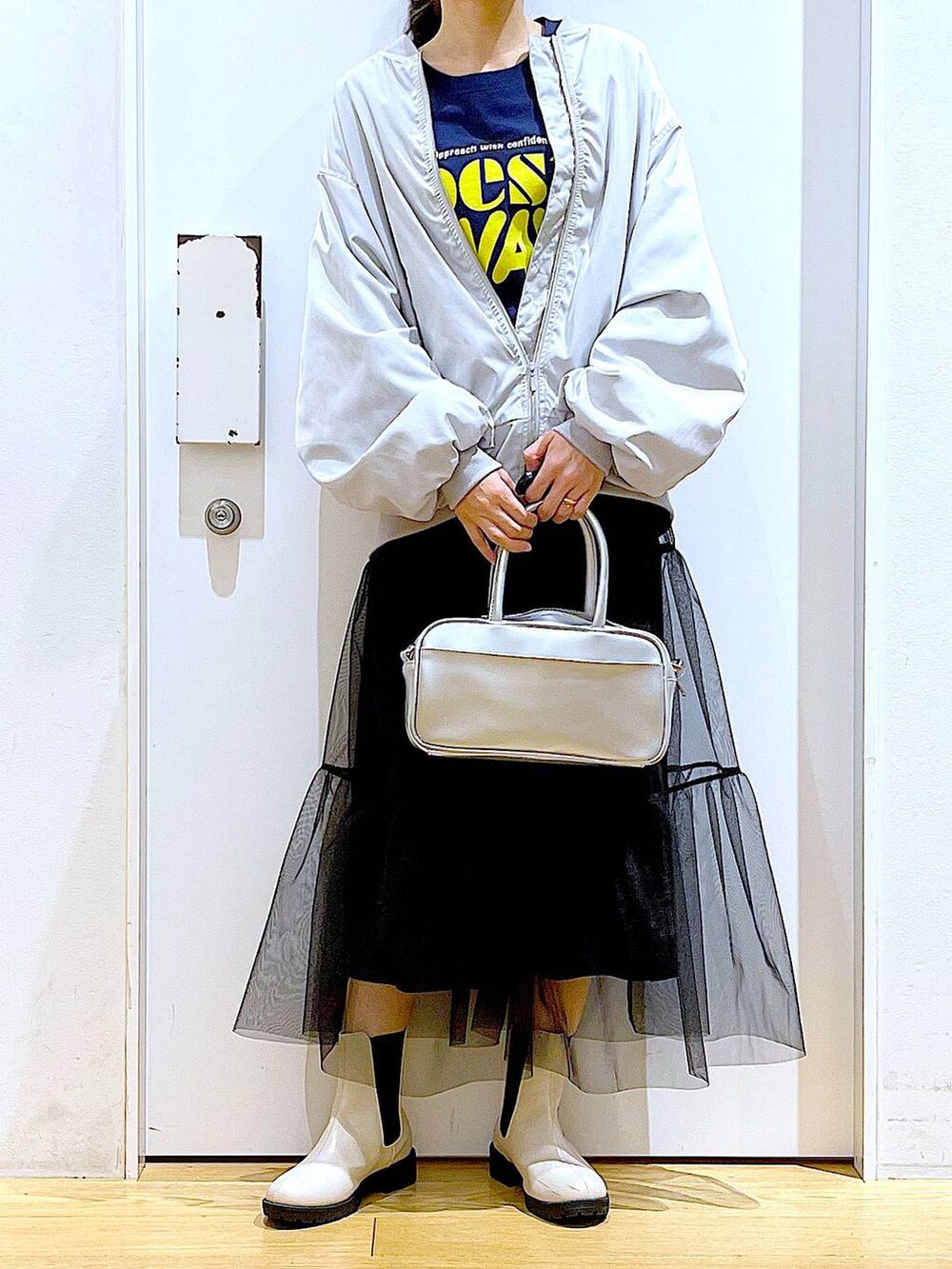 シルバー系のショルダーバッグ、グレー系のMA-1、ベージュ系のブーツを着用したレディースの春コーディネートの6枚目の写真