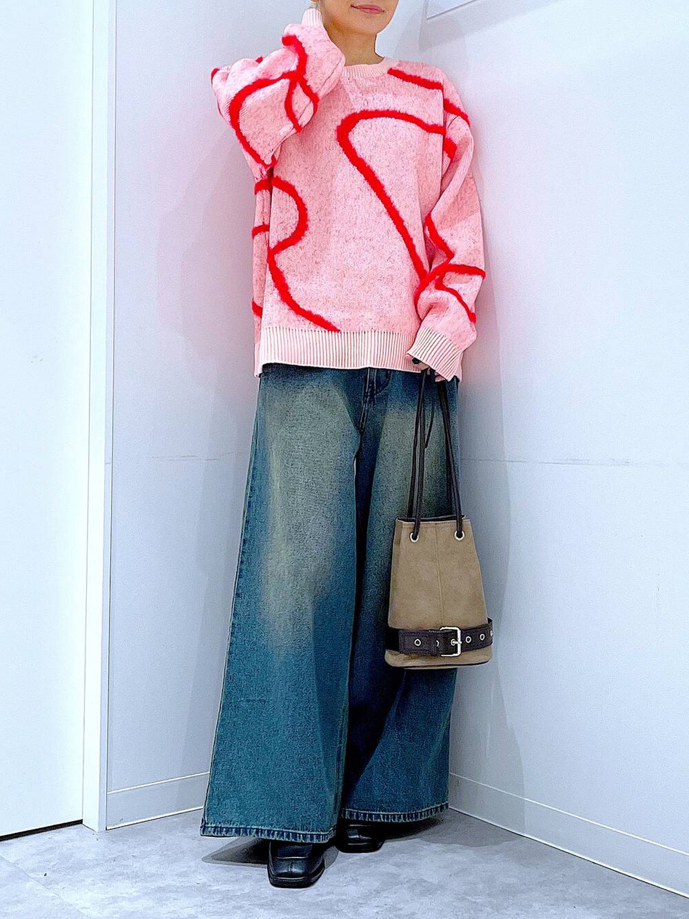 ブルー系のデニムパンツ、ブラック系のブーツ、ベージュ系のハンドバッグを着用したレディースの冬コーディネートの6枚目の写真