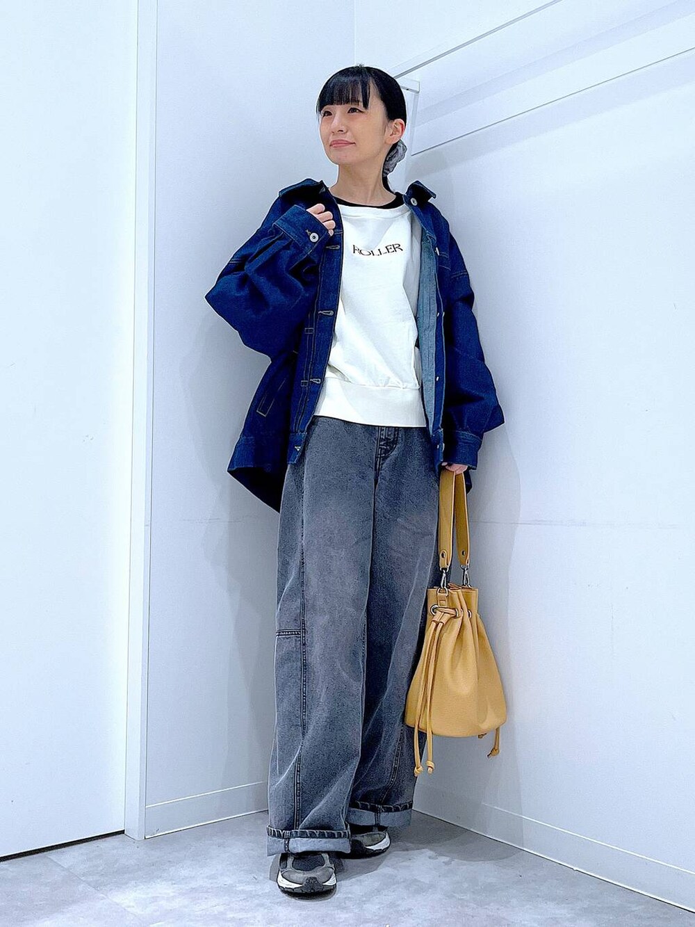 ブルー系のデニムジャケット、ブラック系のデニムパンツ、ブラウン系のショルダーバッグを着用したレディースの春コーディネートの2枚目の写真