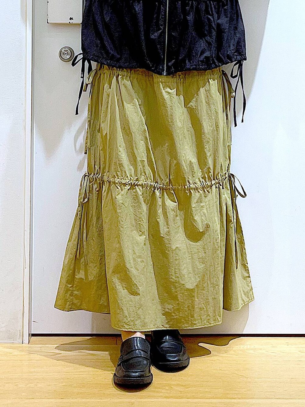 ブラック系のショルダーバッグ、ブラック系のローファー、イエロー系のスカートを着用したレディースの秋コーディネートの8枚目の写真