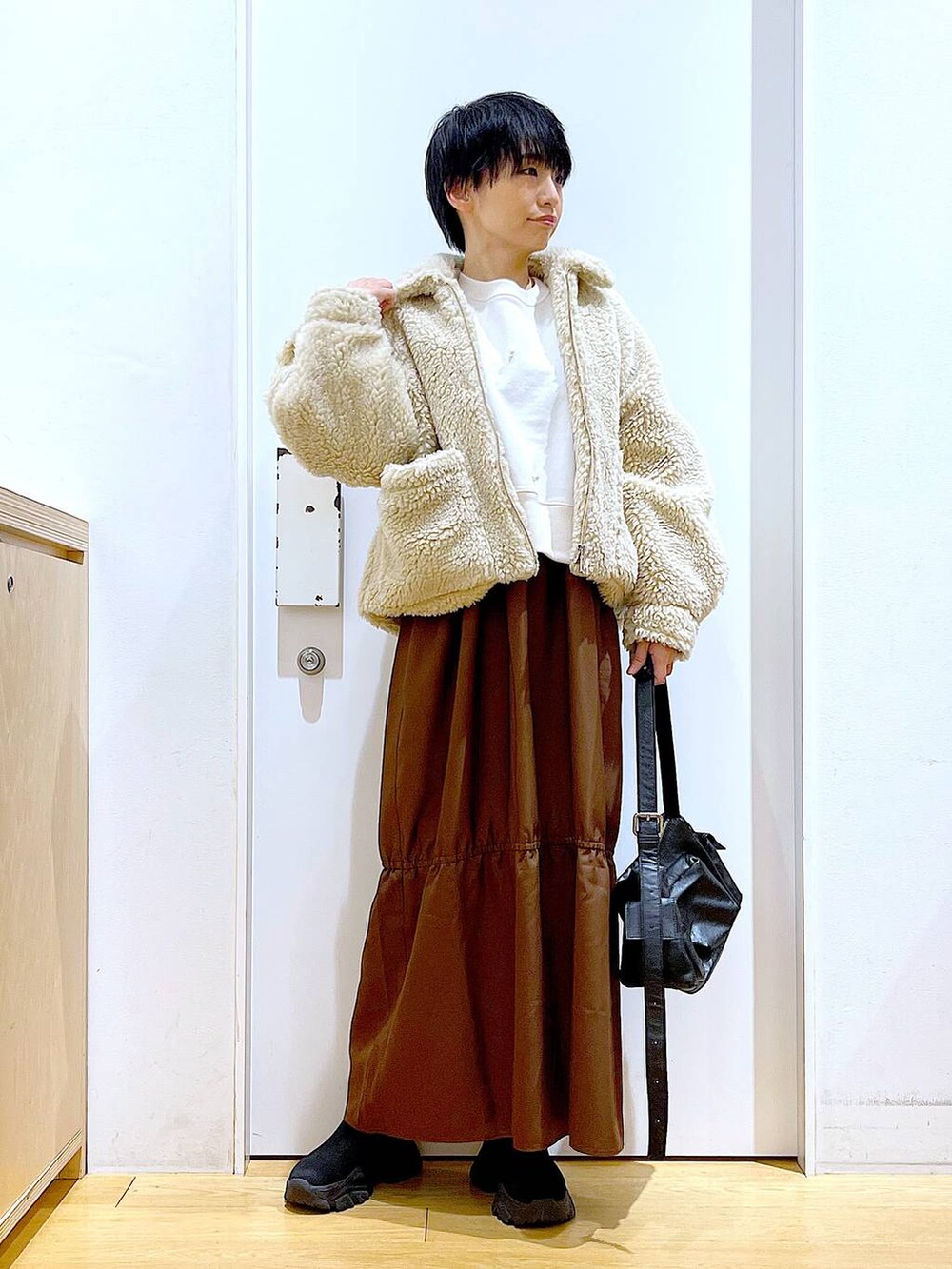 ホワイト系のブルゾン、ホワイト系のスウェット、ブラック系のブーツを着用したレディースの冬コーディネートの2枚目の写真