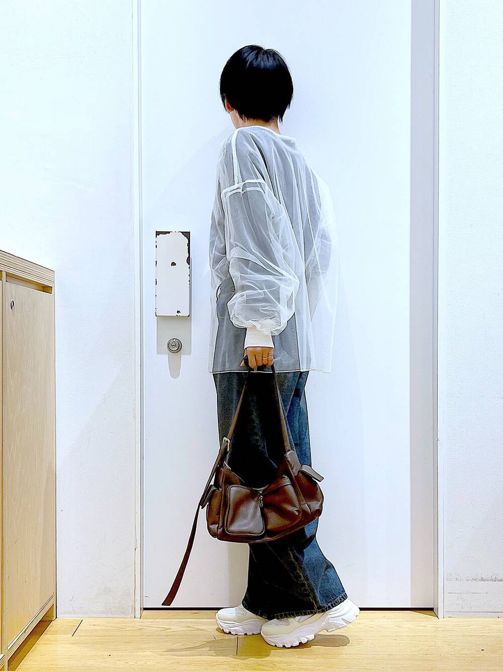 ブルー系のデニムパンツ、ブラウン系のショルダーバッグ、ホワイト系のスニーカーを着用したレディースの春コーディネートの3枚目の写真